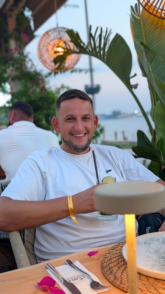 Alex smiling, relaxed, at a table outdoors